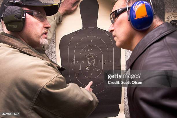Marksmanship instructor Craig Marshall scores Hector Torres' target after he fired his pistol to qualify for an Illinois concealed carry permit on...
