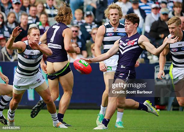 Lachie Neale of the Dockers kicks the ball as Nathan Fyfe of the Dockers loses his shorts during the round two AFL match between the Geelong Cats and...