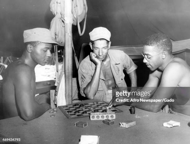 Pvt Jonathan G Moore, Sgt Mose E DeLaine, and Sgt Willie Mr Arceneaux play checkers while being stationed at a Marshalls Army base, US Army Base,...
