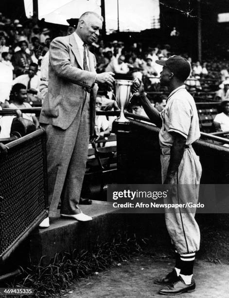 Full length portrait of US representative Arthur Wergs Mitchell presenting a cup to captain Sylvester Hall of the Police Boy's Club baseball team...