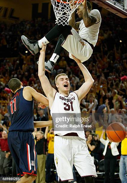 Jahii Carson of the Arizona State Sun Devils hangs from the rim after a slam dunk as teammate Jonathan Gilling holds him up in celebration of a 69-66...