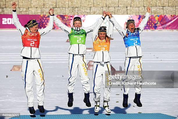 Gold medalists Ida Ingemarsdotter, Emma Wiken, Anna Haag and Charlotte Kalla of Sweden celebrate on the podium during the flower ceremony for the...