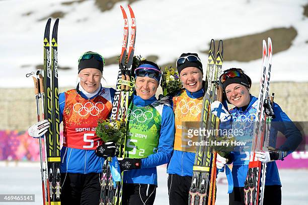 Silver medalists Anne Kylloenen, Aino-Kaisa Saarinen, Kerttu Niskanen and Krista Lahteenmaki of Finland celebrate on the podium during the flower...