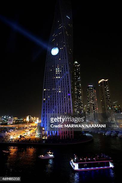 Spotlight illuminates French urban climber Alain Robert, also known as "Spider-Man", as he scales the Cayan Tower, the world's tallest twisted...