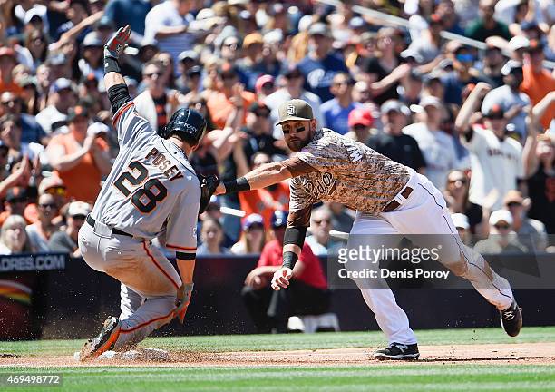 Buster Posey of the San Francisco Giants slides safely into third base ahead of the tag of Will Middlebrooks of the San Diego Padres during the third...