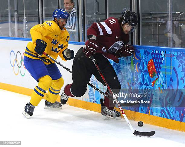 Kaspars Daugavins of Latvia handles the puck against Niklas Kronwall of Sweden in the first period during the Men's Ice Hockey Preliminary Round...