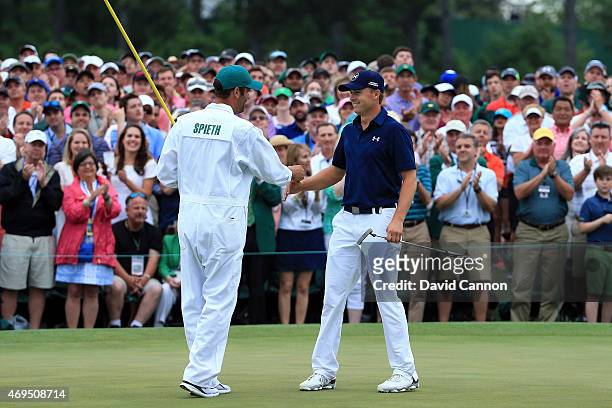 Jordan Spieth of the United States celebrates with his caddie Michael Greller on the 18th green after his four-stroke victory at the 2015 Masters...
