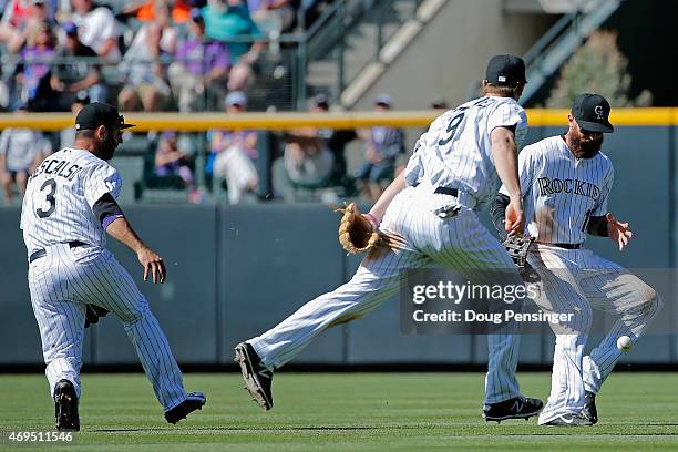 Daniel Descalso, DJ LeMahieu and Charlie Blackmon of the Colorado Rockies are unable to make a play on pop fly as Dexter Fowler of the Chicago Cubs...