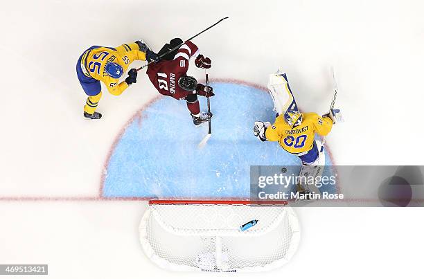 Lauris Darzins of Latvia shoots against Niklas Kronwall and Henrik Lundqvist of Sweden in the second period during the Men's Ice Hockey Preliminary...