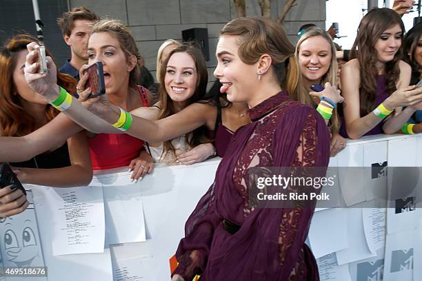 Model/actress Cara Delevingne poses for a selfie photo with fans attending The 2015 MTV Movie Awards at Nokia Theatre L.A. Live on April 12, 2015 in...