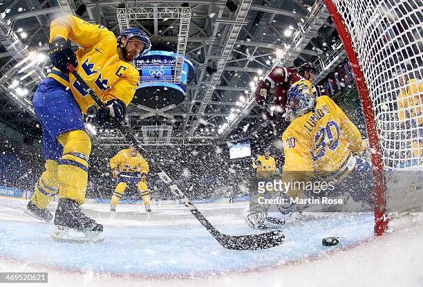 Lauris Darzins of Latvia shoots against Niklas Kronwall and Henrik Lundqvist of Sweden in the second period during the Men's Ice Hockey Preliminary...