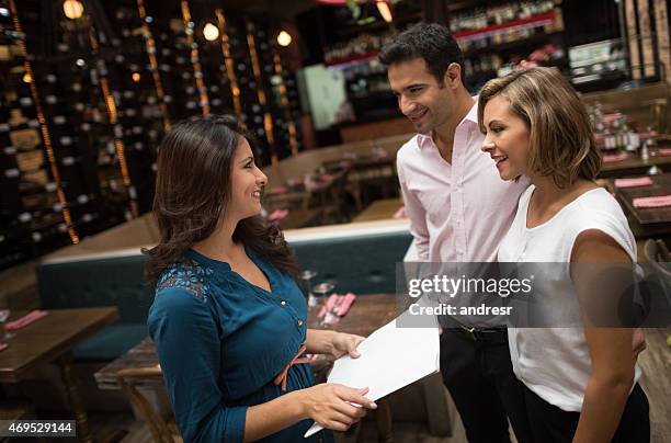 couple at a restaurant talking to the hostess - hostess stock pictures, royalty-free photos & images