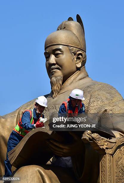 South Korean workers wipe down a bronze statue of King Sejong, the 15th-century Korean king, during a street and park clean-up event for the spring...