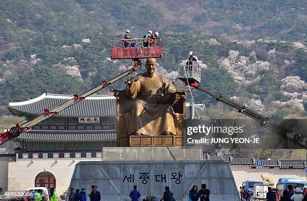 South Korean workers use hoses to wash a bronze statue of King Sejong, the 15th-century Korean king, during a street and park clean-up event for the...