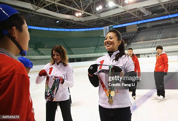 Laureus World Sports Academy member Yang Yang and Nadia Comaneci gives a child a medal during a visit to a Laureus Sport For Good Project prior to...