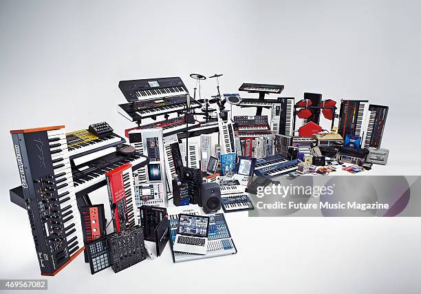 Selection of instruments and audio recording equipment photographed on a white background, including keyboard synthesizers, laptops, monitors and...