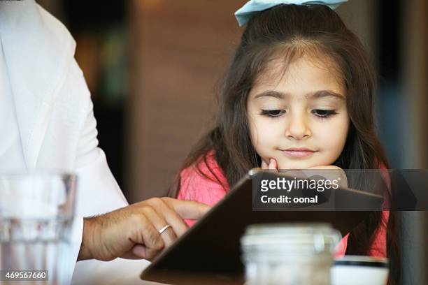 arabian father and daughter enjoying leisure time in a cafe - arabia saudi stock pictures, royalty-free photos & images
