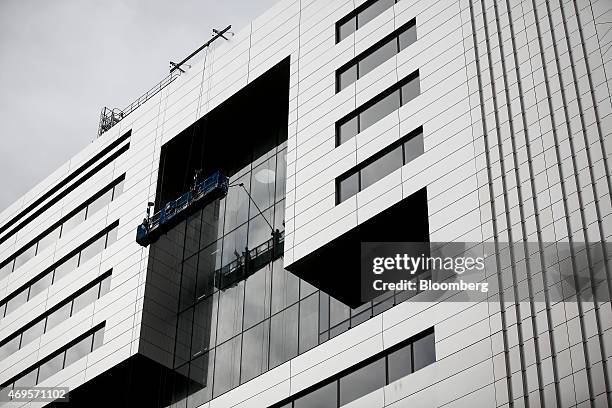 Workers stand in a suspended gantry as they clean the newly installed windows of No. 5 Broadgate, an office complex to be occupied by UBS AG, as...