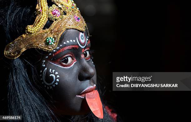 An Indian girl dressed as Hindu godess Kali rehearses prior to participating in a religious rally to celebrate the Gajan Festival in Kolkata on April...