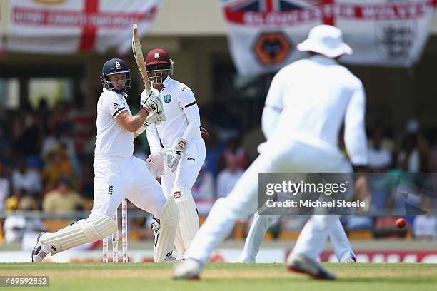 Joe Root of England pulls a delivery behind square off the bowling of Sulieman Benn of West Indies as wicketkeeper Denesh Ramdin looks on during day...