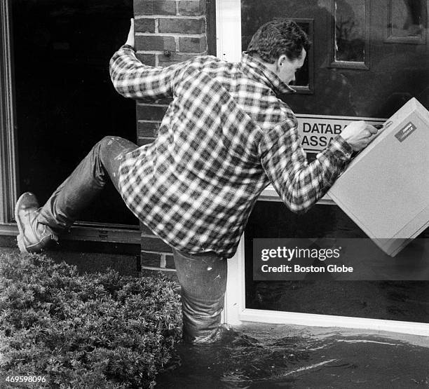 David Desnoyers, who owns a publishing company on the edge of the Merrimack River, steps out of his office window with computer equipment into...