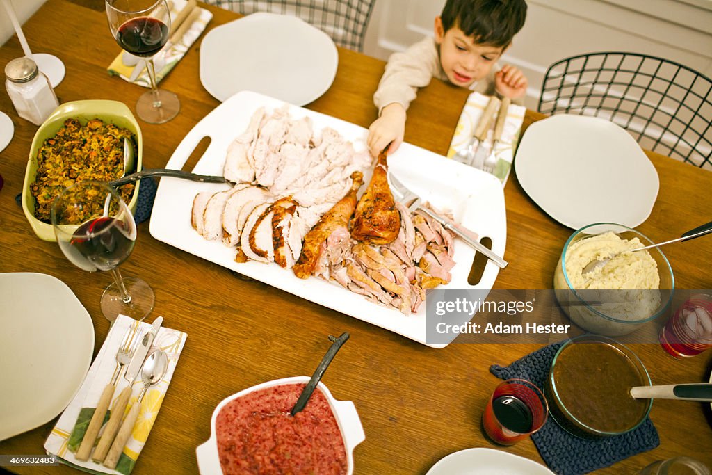 A young boy reaching for a piece of turkey inside