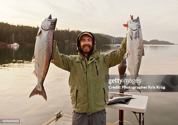 fisherman holding up king salmon chinook fish - catch of fish stock pictures, royalty-free photos & images