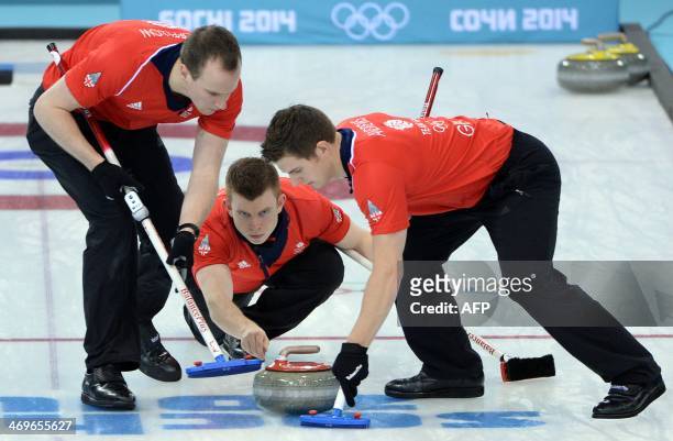 Great Britain's Greg Drummond trows the stone as team mates Michael Goodfellow and Scott Andrews sweep the ice during the Men's Curling Round Robin...