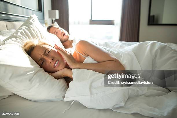 man snoring, woman frustrated-couple in bed - snoring husband stock pictures, royalty-free photos & images