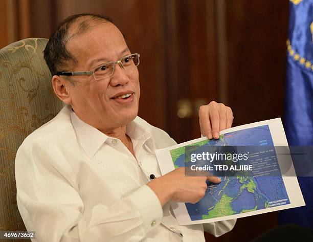 Philippine President Benigno Aquino points to a copy of China's nine-dash line map during an interview with AFP at Malacanang Palace in Manila on...