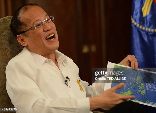 Philippine President Benigno Aquino reacts as he shows a copy of China's nine-dash line map during an interview with AFP at Malacanang Palace in...