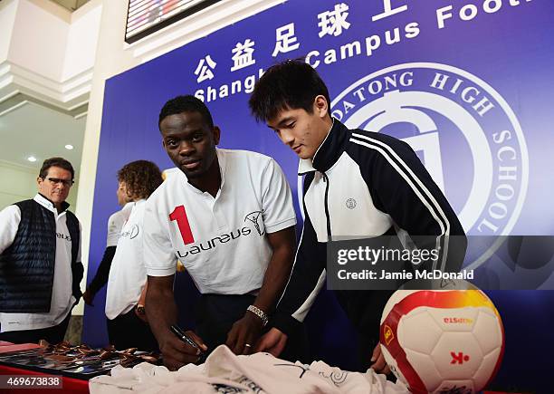 Former footballer Louis Saha of France signs a t-shirt during a Laureus Shanghai Football Campus Tour prior to the Laureus World Sports Awards 2015...