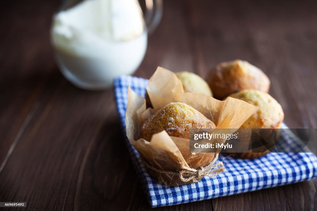 Homemade muffins and jug of milk on wood table