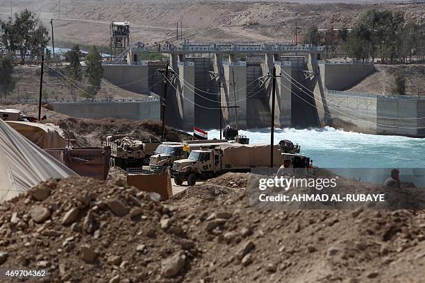 Iraqi army vehicles are stationned in front of a dam on the Euphrates River on April 14, 2015 in the Garma district, west of the Iraqi capital...