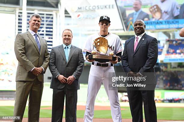 Christian Yelich of the Miami Marlins accepts his Rawlings Gold Glove award from Marlins GM Dan Jennings and President of Baseball Operations Michael...