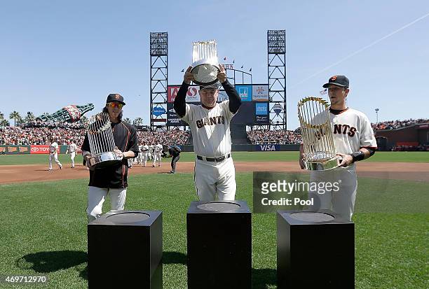 Tim Lincecum, Bruce Bochy and Buster Posey of the San Francisco Giants leads the team on to the field carryin their three World Series Trophies prior...