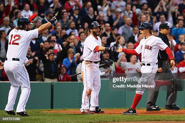 Brock Holt of the Boston Red Sox is celebrates with his teammates Mike Napoli and Dustin Pedroia after scoring a run against the Washington Nationals...