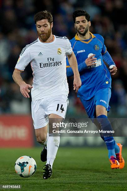 Xabi Alonso of Real Madrid CF runs for the ball ahead Angel Lafita of Getafe CF during the La Liga match between Getafe CF and Real Madrid CF at...