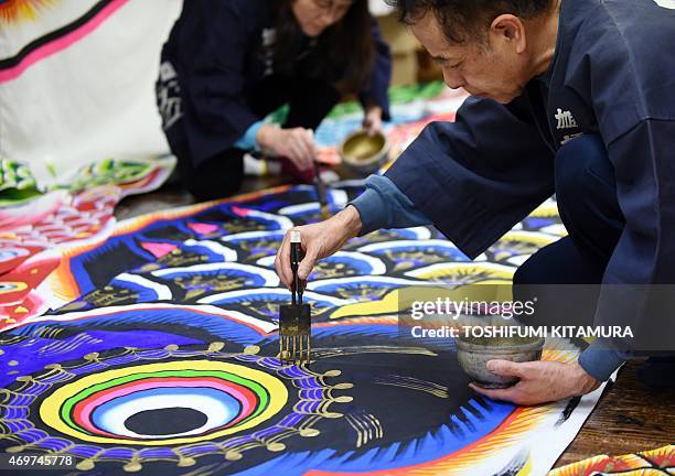 Masaru Hashimoto puts gold paint onto a carp streamer at a factory in Kazo, Saitama prefecture, some 50-kilometre north of Tokyo on April 15, 2015....