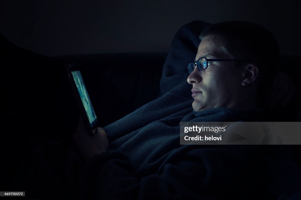 Junger Mann mit digitalen tablet bei Nacht