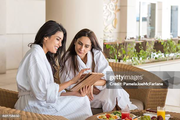middle eastern women with computer tablet having spa meal together - middle eastern culture stock pictures, royalty-free photos & images