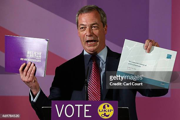 Independence Party leader Nigel Farage holds up his party manifesto and budget policy document during the launch of his party's election manifesto on...
