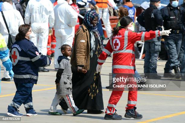 Italian Red Cross operators give first aid to immigrants as they arrives on April 15, 2015 in the Italian port of Messina in Sicily. Italian...