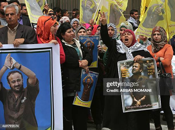 Palestinian protesters wave flags and placards bearing portraits of Fatah leader Marwan Barghuti, during a march to mark the anniversary of his...