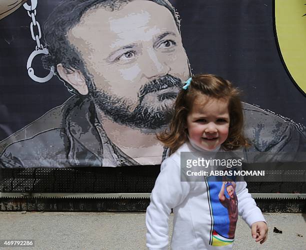 Tala, the granddaughter of Fatah leader Marwan Barghuti stands in front of a poster bearing his portrait, during a march to mark the anniversary of...