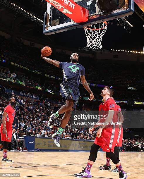 LeBron James of the Eastern Conference All-Stars dunks against Kevin Love of the Western Conference All-Stars during the 2014 NBA All-Star Game as...