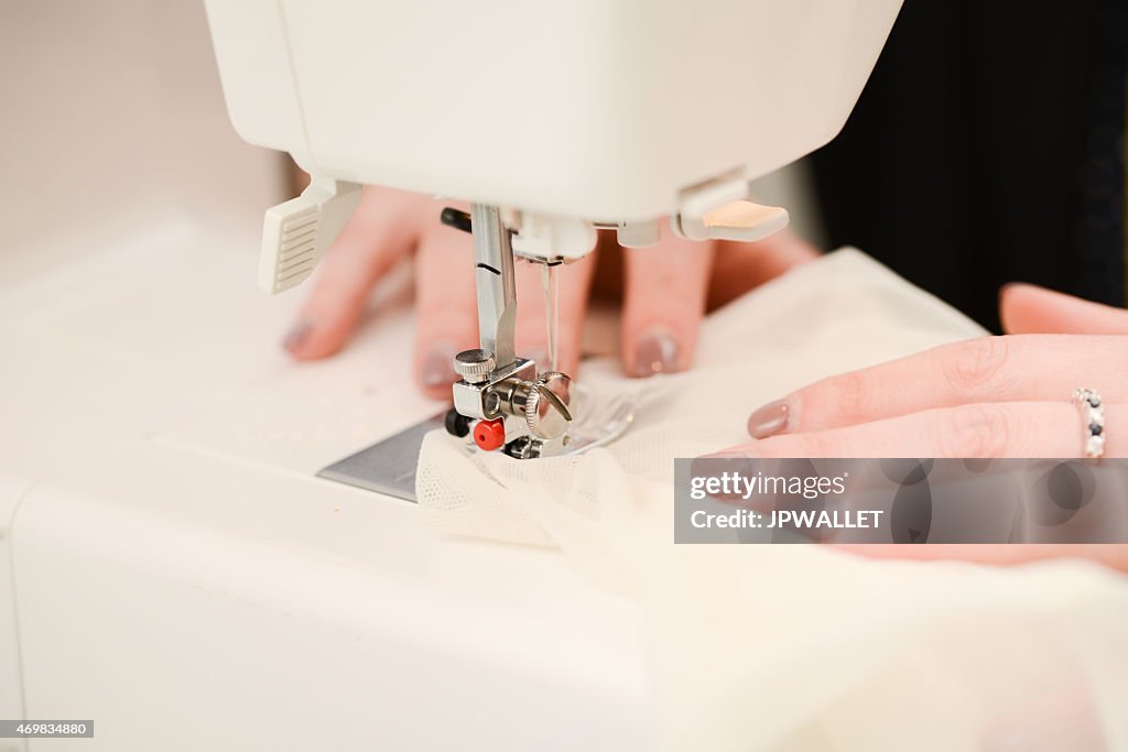 Close up hands of young seamstress working on sewing machine