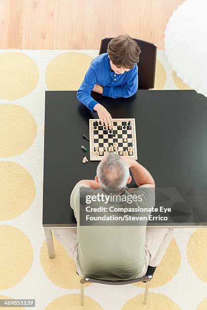 grandfather and grandson playing chess - chess board overhead stock pictures, royalty-free photos & images