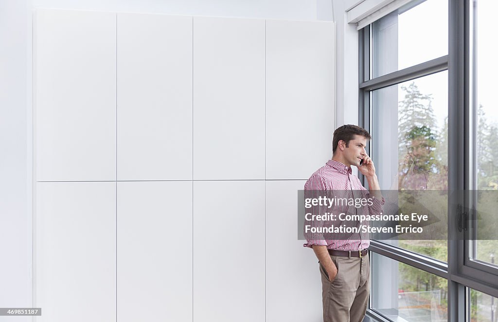 Businessman talking on cell phone by window