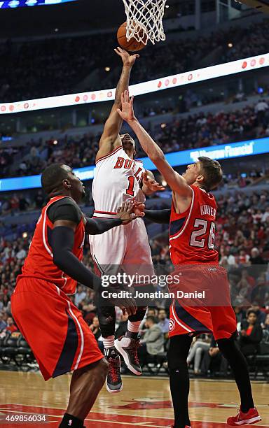 Derrick Rose of the Chicago Bulls shoots over Paul Millsap and Kyle Korver of the Atlanta Hawks at the United Center on April 15, 2015 in Chicago,...